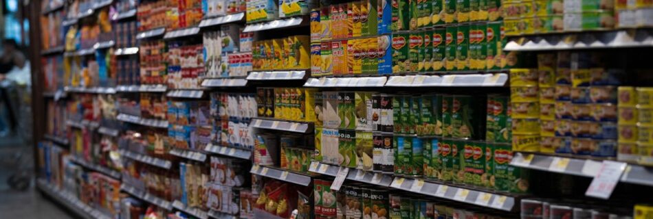 A supermarket aisle filled with various canned goods on shelves, showcasing retail diversity.